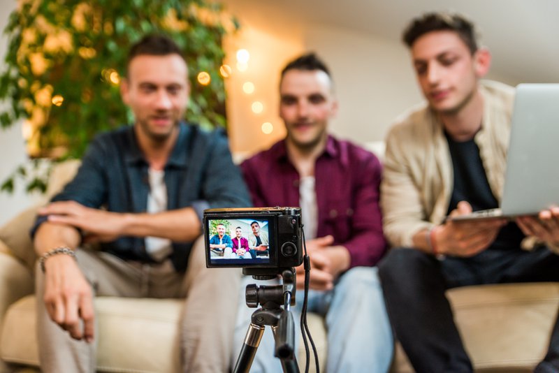 Groupe d'influenceurs de réseaux sociaux filmant un vlog à la maison, discutant et examinant un produit