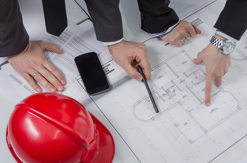 Plan rapproché des mains d'architectes révisant des plans de projet de maison