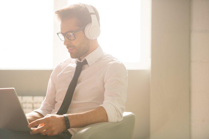 Jeune expert en référencement concentré avec du chaume assis dans un fauteuil et utilisant un ordinateur portable tout en prenant des statistiques sur des sites Web