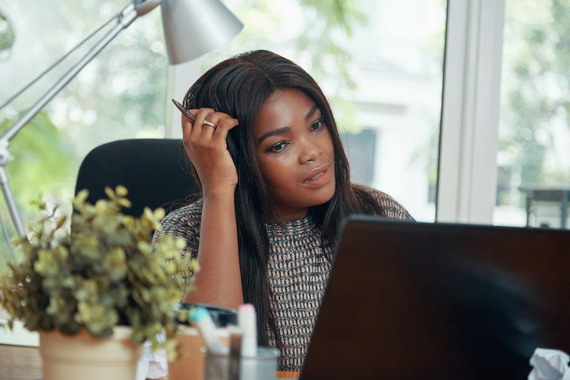 数字营销部门女主管在笔记本电脑屏幕上阅读合同细节时挠头