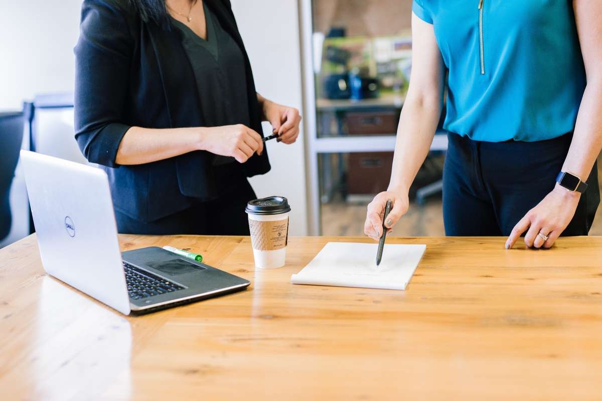 Deux personnes en tenue de soirée se tiennent près d'une table. L'un d'eux semble taper avec assurance avec un stylo sur la table.