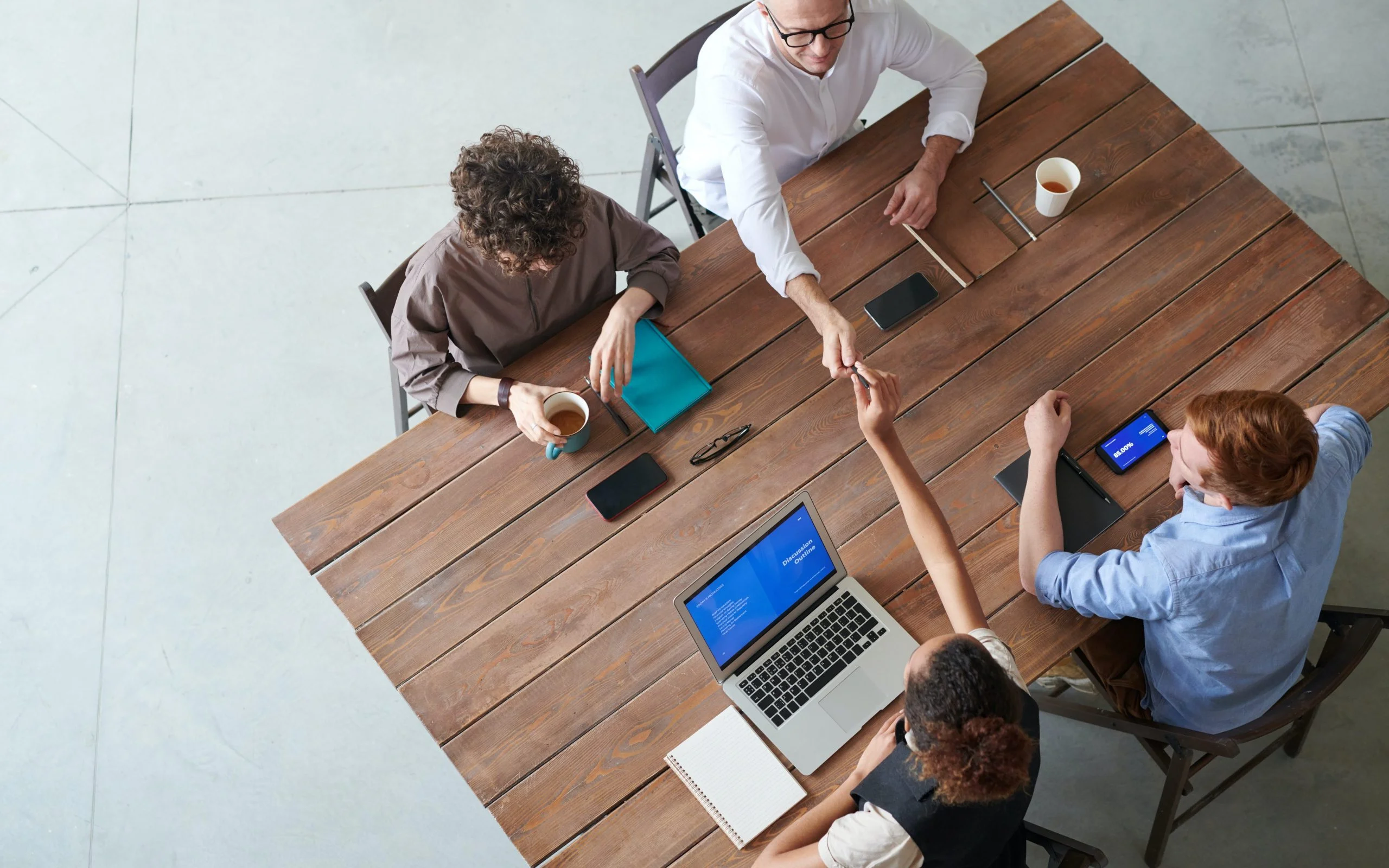 4 個人坐在一張桌子旁，一起處理一個項目