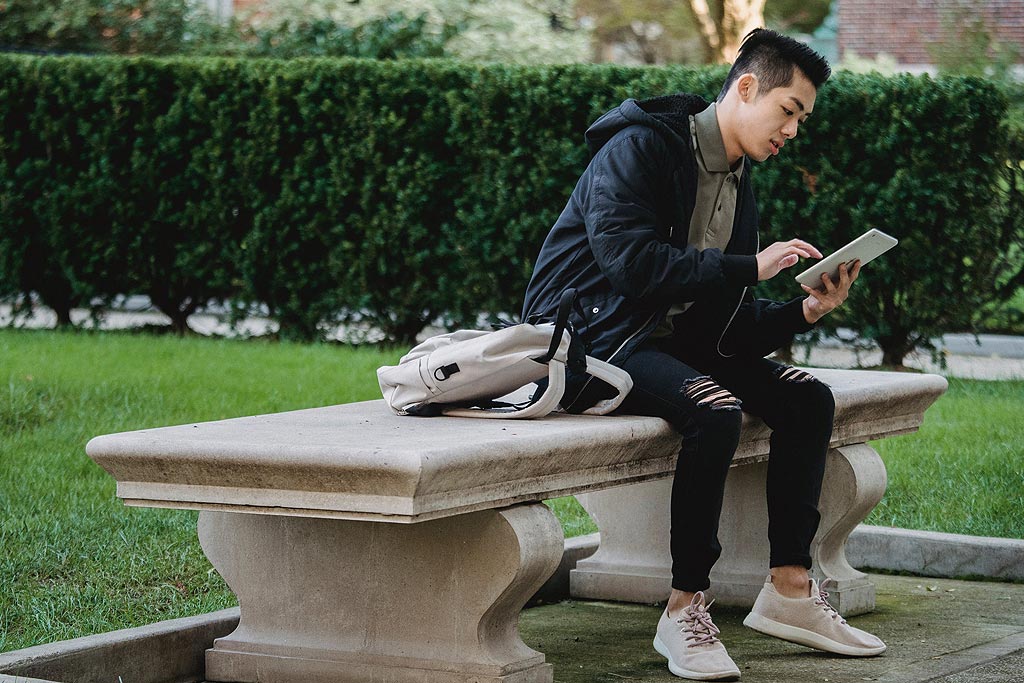 使用 iPad 坐在長凳上的人