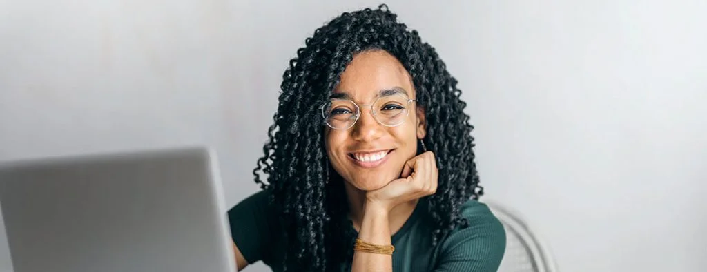 Persoană care zâmbește în cameră în timp ce este un computer