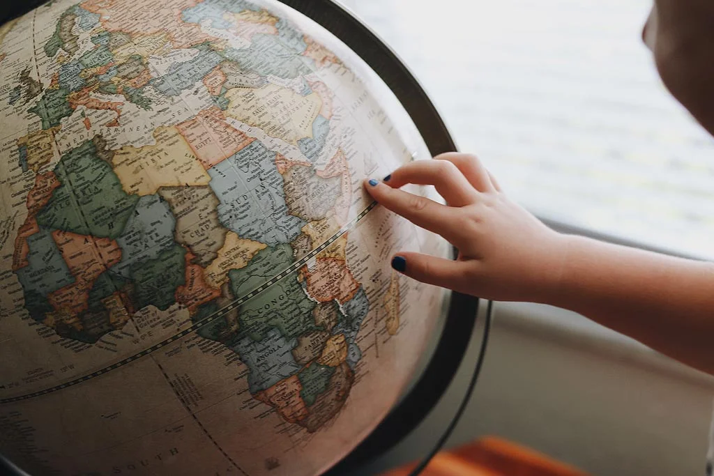 Küre üzerinde bir yeri işaret eden kişi