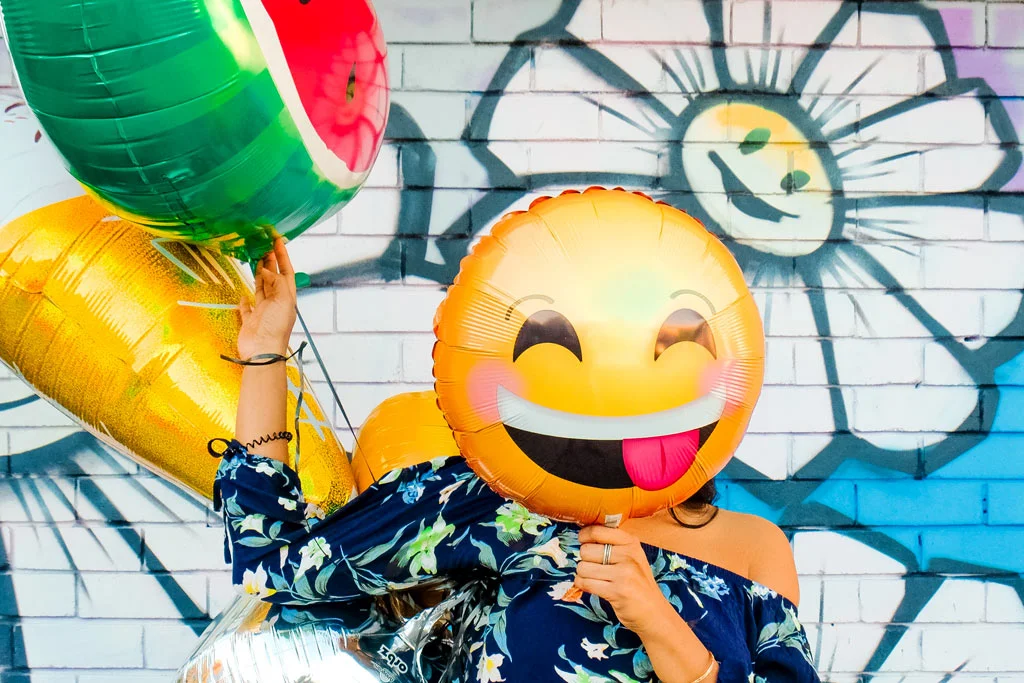 persoană care ține în mână un balon cu fața zâmbitoare acolo