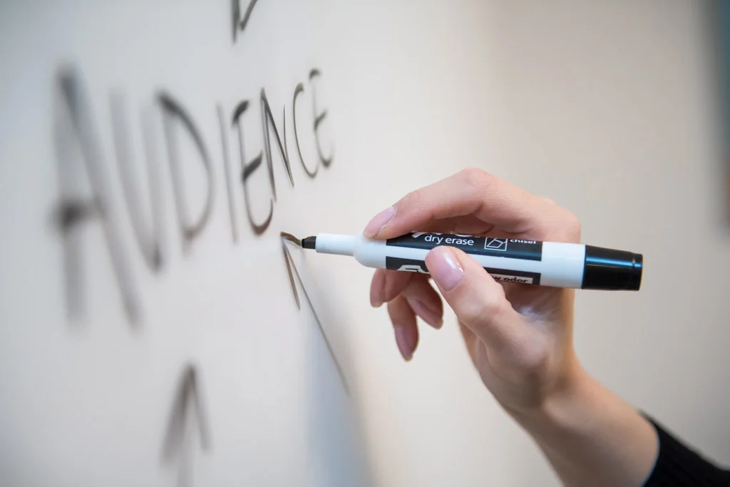 Persoană care scrie o tablă albă cu publicul pe ea