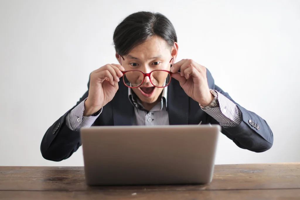 Person zieht das Glas herunter und schaut erstaunt auf einen Computerbildschirm