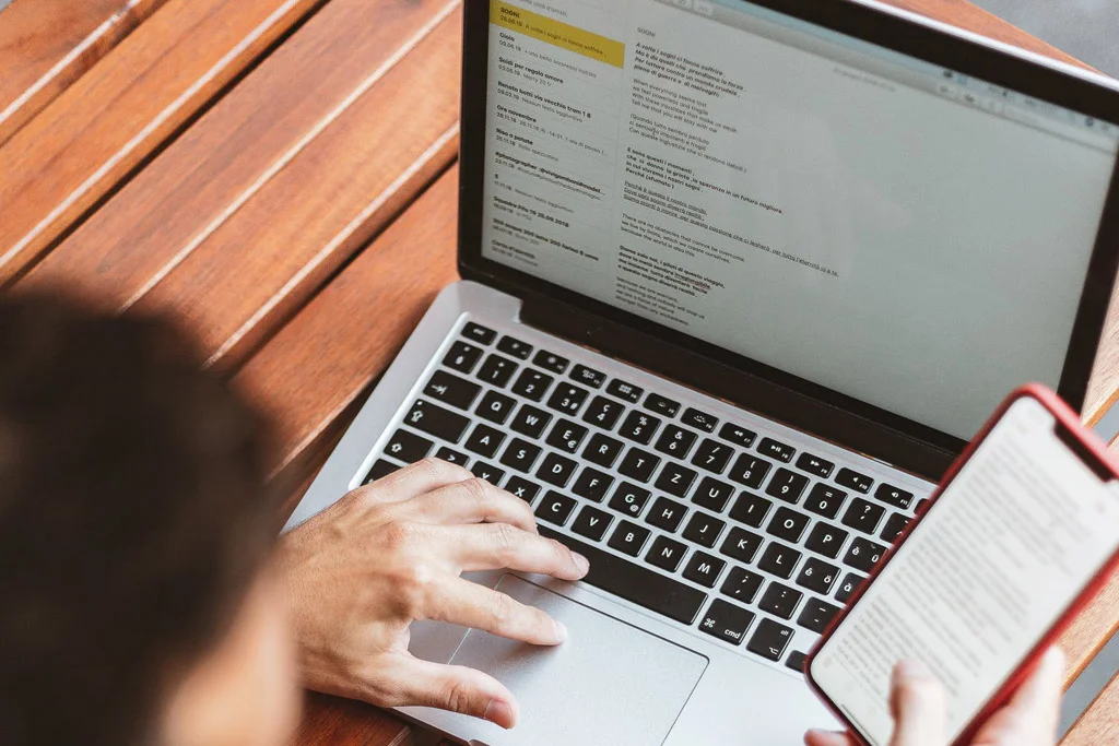 شخص يعمل على الهاتف والكمبيوتر المحمول في نفس الوقت