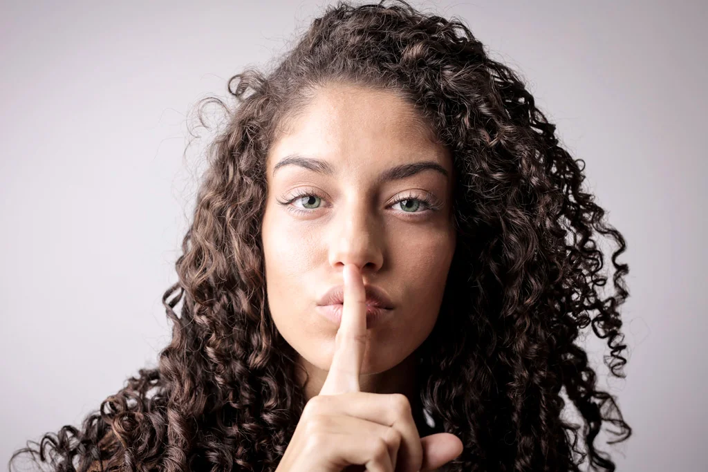 Persona con un dito in bocca che tace