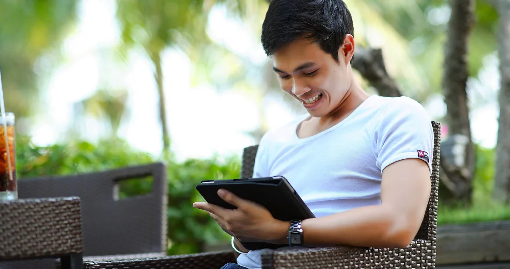 شخص في الخارج يبتسم على جهاز لوحي