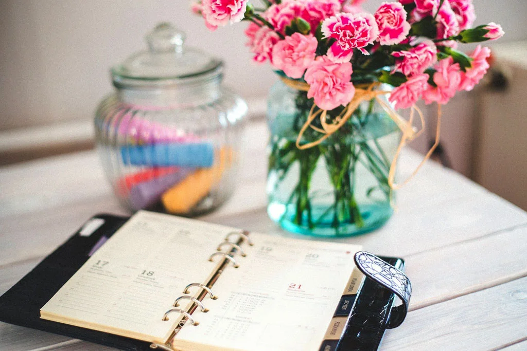 Calendario su un tavolo con fiori in vaso dietro il calendario
