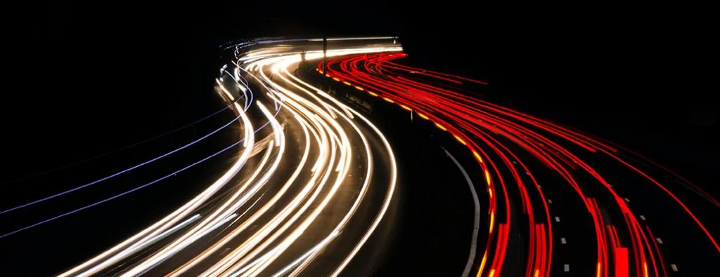 Auto che lasciano strisce di luce che guidano velocemente