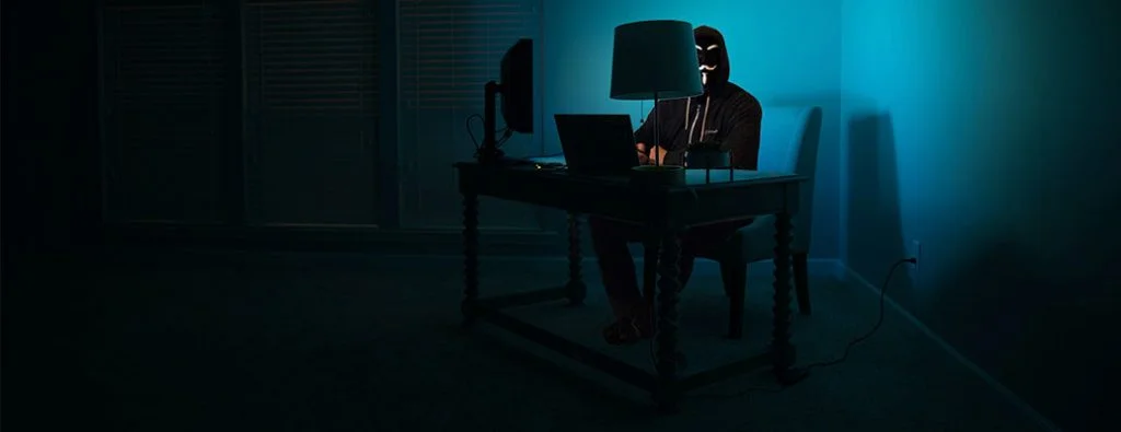 暗闇の中でコンピューターをハッキングする人
