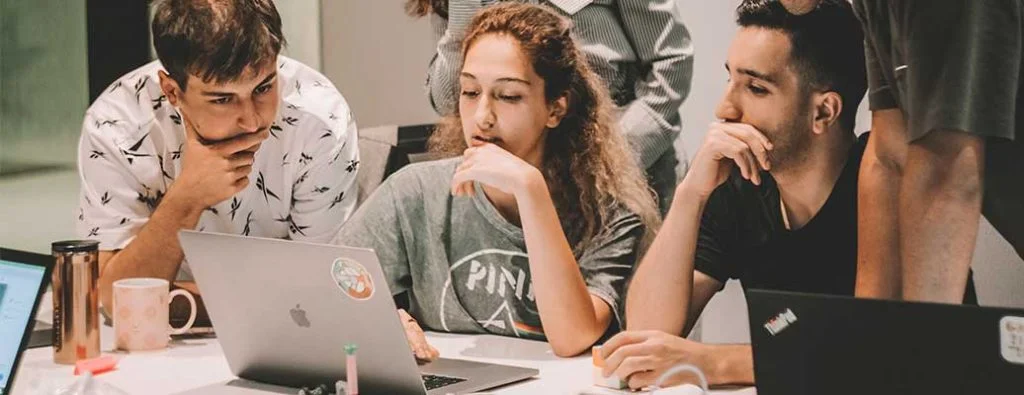 un tas de gens qui regardent et travaillent tous sur un ordinateur