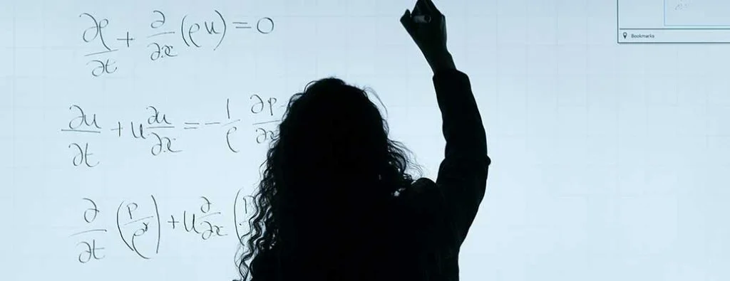 une personne qui fait des maths sur un tableau blanc
