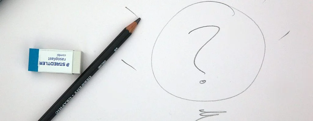 鉛筆と消しゴムが横にある紙に書かれた疑問符