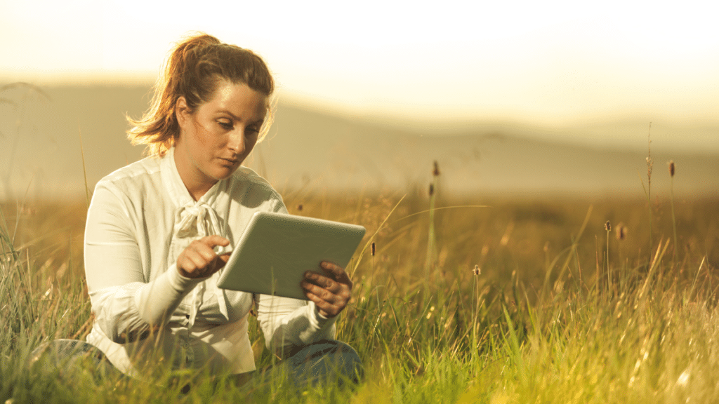 一个女人独自坐在灌木丛中,手里拿着平板电脑