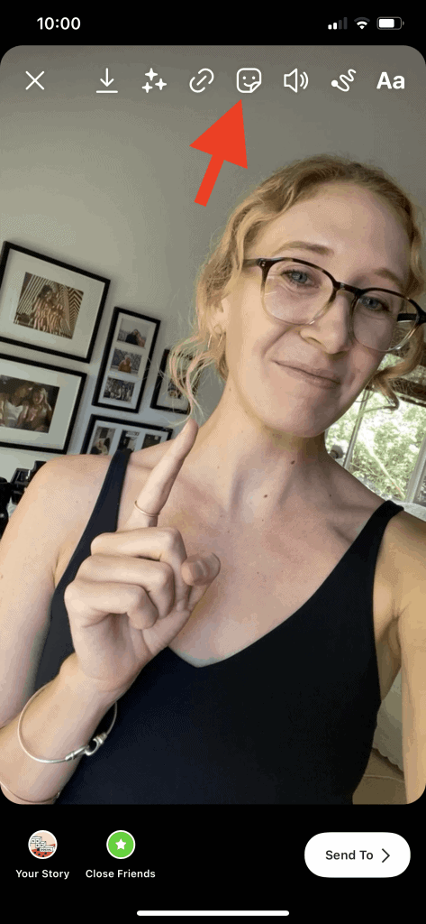 ภาพหน้าจอของ Instagram Story ที่แสดงแถบด้านบนที่ด้านบนของหน้าพร้อมลูกศรสีแดงชี้ไปที่ปุ่มสติกเกอร์