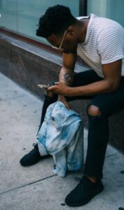 Mann sitzt, während er Smartphone benutzt