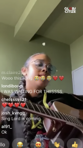 Uno screenshot del cantante H.E.R. suonare la chitarra e cantare su Instagram dal vivo. I commenti e le reazioni di supporto degli spettatori sono visibili.