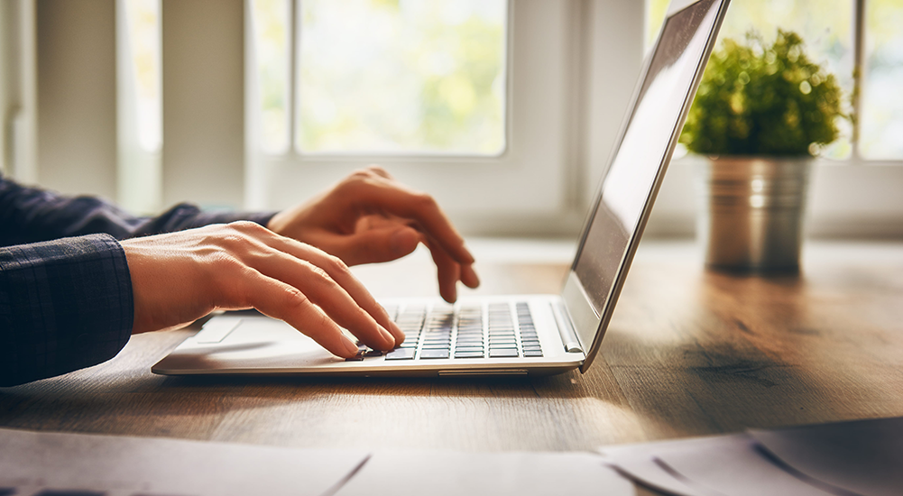 Cerca de manos escribiendo en la computadora portátil.