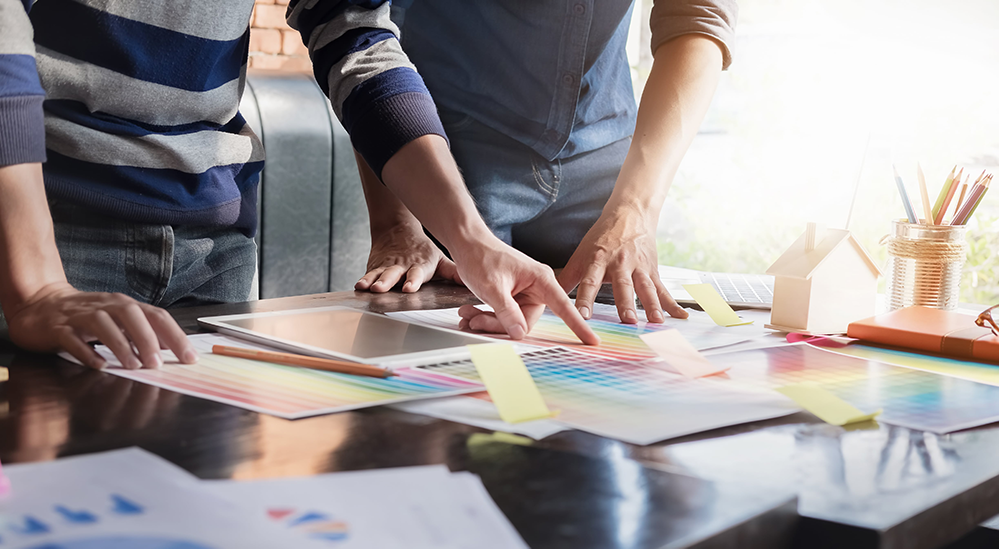 Dos empleados varones comparan muestras de color para un proyecto.