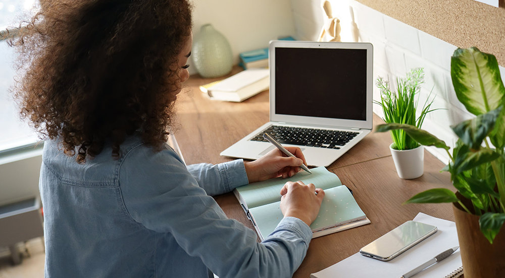 Mujer sentada en un escritorio escribiendo notas.