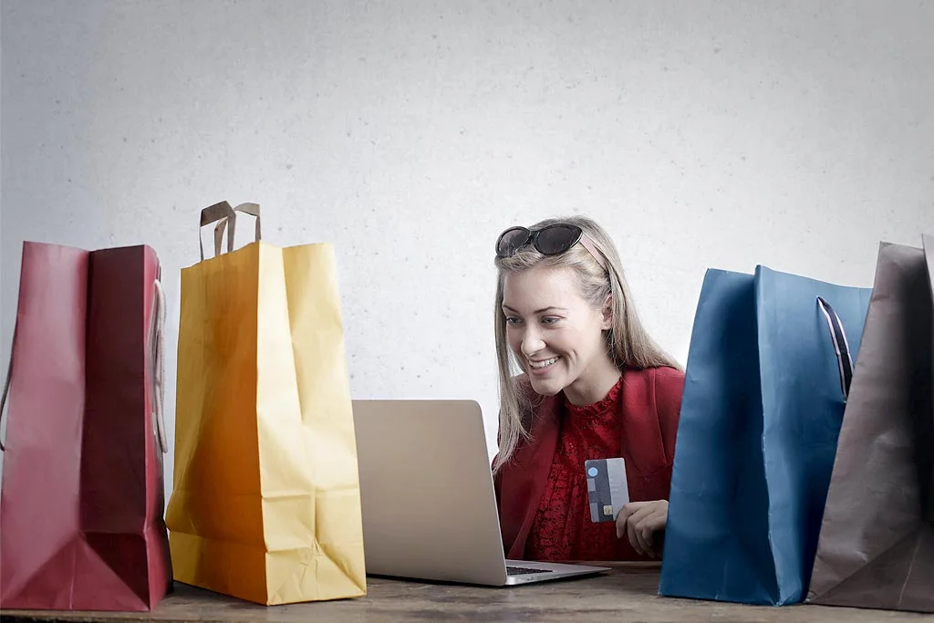 Person hält. Kreditkarte mit Einkaufstüten rundherum