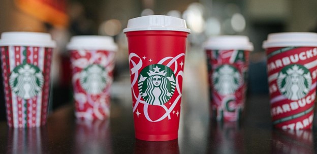 Neşeli kırmızı, yeşil ve beyaz tasarımlarla önceki yıllardan Starbucks tatil bardaklarının görüntüsü.