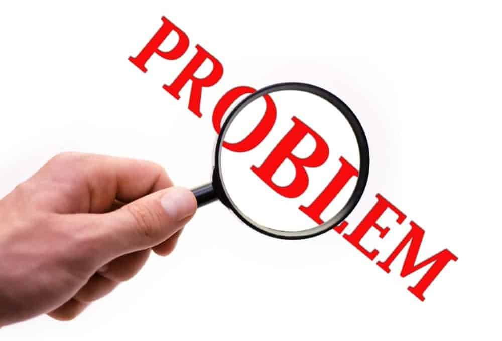 手拿着放大镜对“问题”一词在白色背景下用粗体红色字母表示。