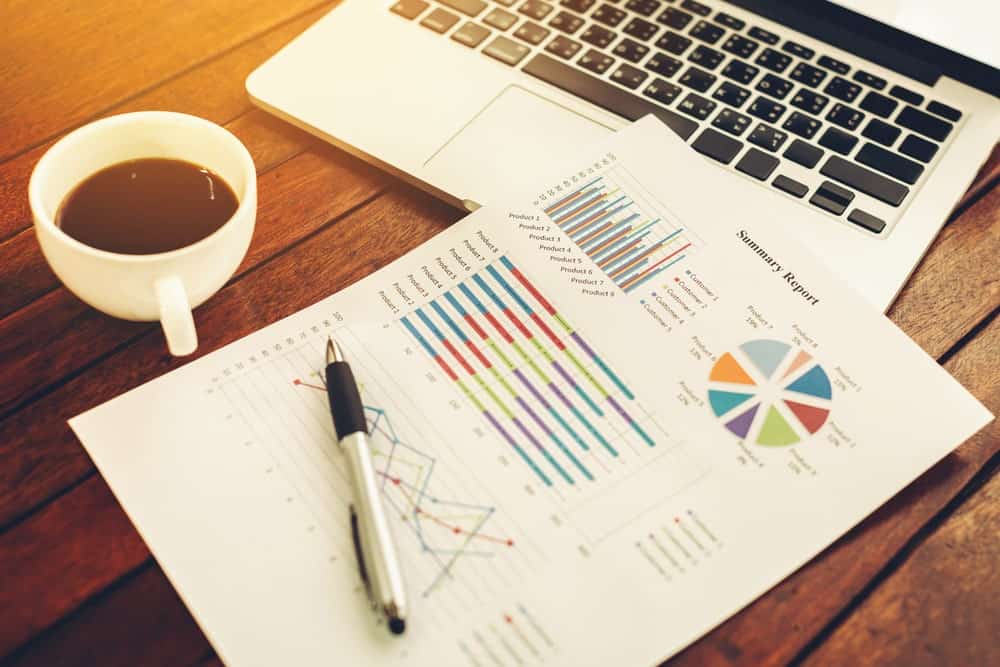 커피 한 잔과 나무 테이블에 노트북과 함께 요약 보고서.