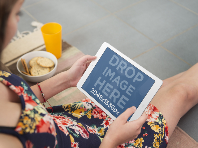نموذج بالحجم الطبيعي لجهاز iPad لفتاة صغيرة جالسة على الأرض باستخدام صورة بيضاء لجهاز iPad Placeit
