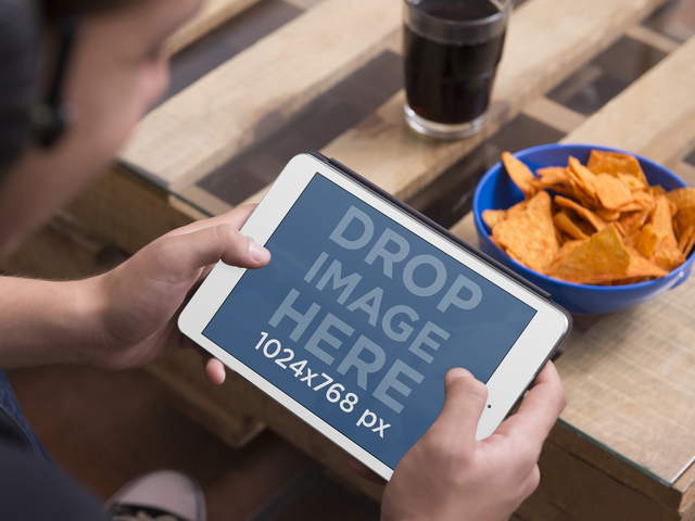 نموذج الكمبيوتر اللوحي للمراهق باستخدام iPad Mini مع وعاء من الرقائق وصورة مكان الصودا