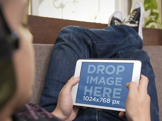 نموذج iPad Mockup يعرض مراهقًا يستخدم iPad أبيض على صورة Couch Placeit Stage
