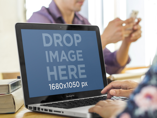 Mockup di Macbook Pro con una donna che lavora mentre un collega sta inviando messaggi all'immagine del palco di Placeit