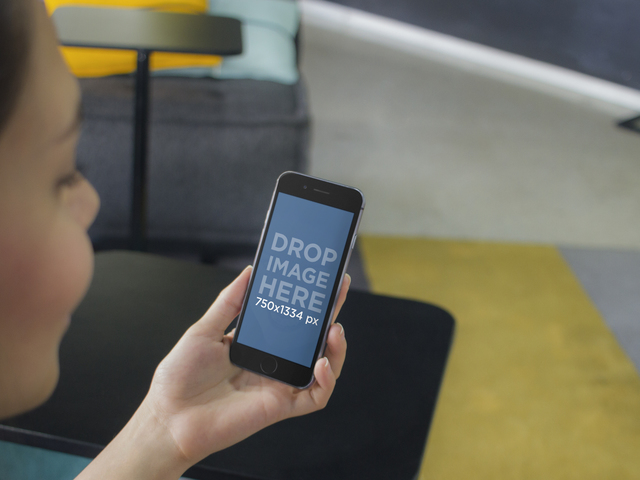 Макет iPhone девушки с черным iPhone 6 в красочной гостиной Placeit Stage Image