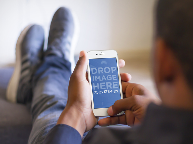 Макет мужчины, расслабляющегося с поднятыми ногами и использующего белый iPhone 6 Placeit Stage Image