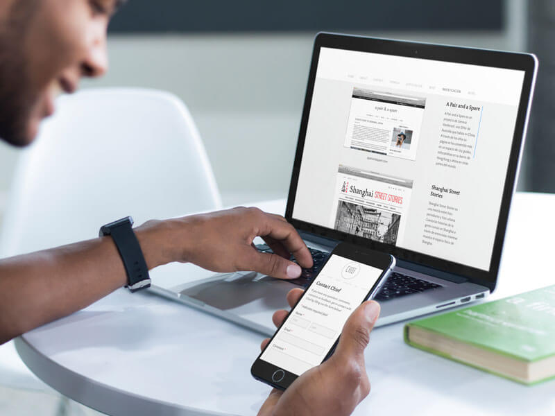 Молодой человек работает над своим ноутбуком Macbook Pro и макетом iPhone