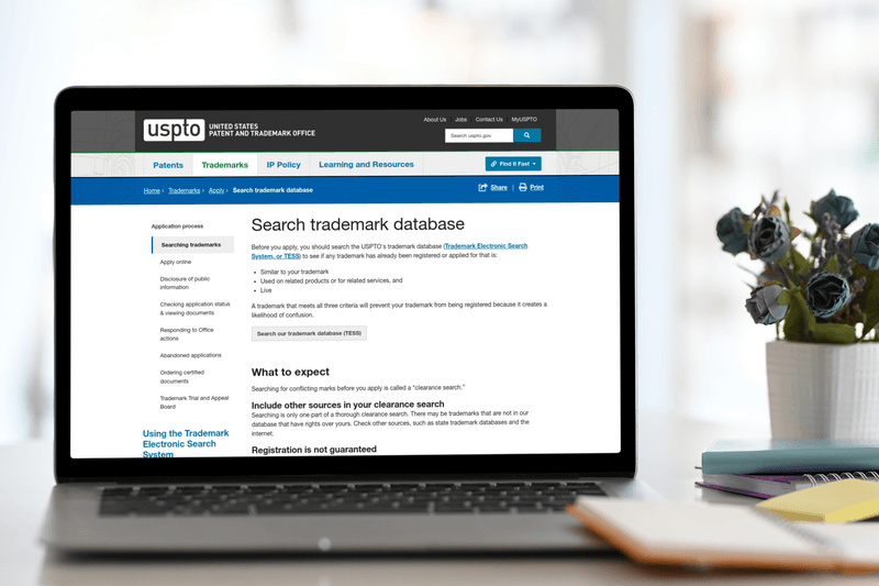 Macbook Air Mockup em uma mesa com o site de pesquisa de marcas registradas da Uspto