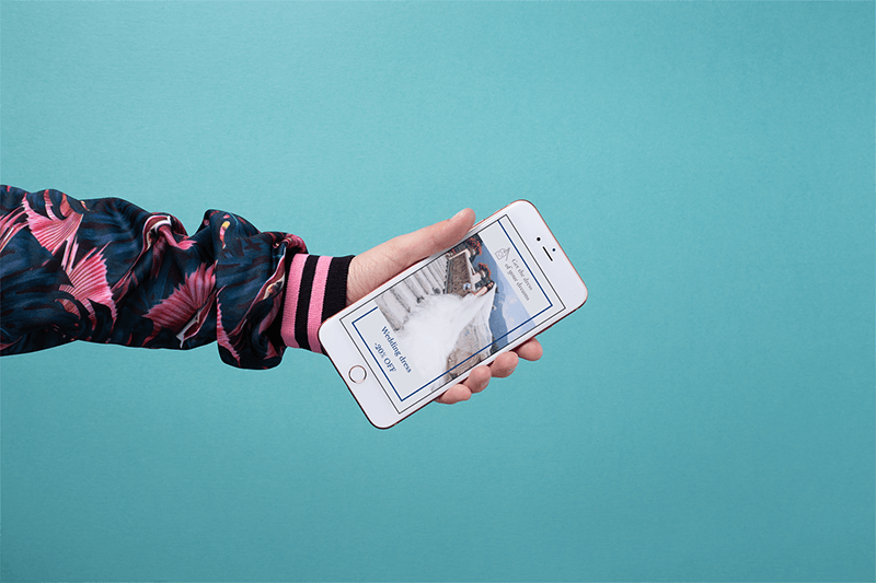 Maquette d'un bras habillé de couleurs vives tenant un Iphone en or