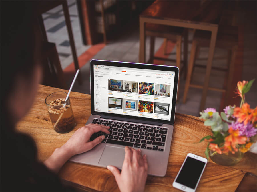 Fotografie peste umăr a unei femei care lucrează cu o machetă Macbook Pro