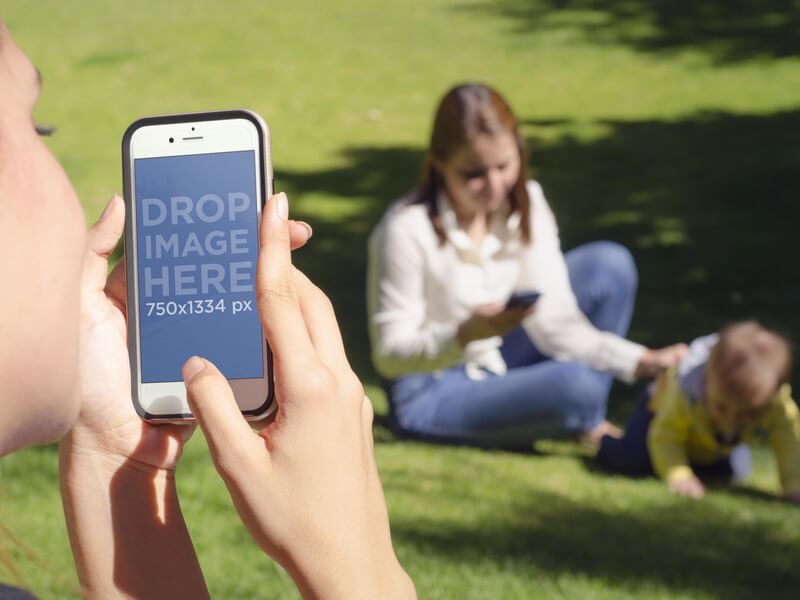 Makieta iPhone'a przedstawiająca dziewczynę fotografującą przyjaciela i dziecko w parku