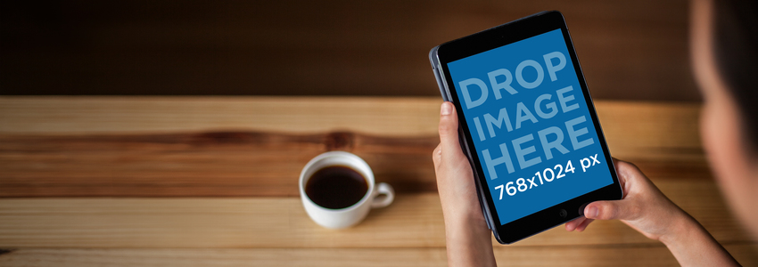 Modell einer Frau, die ein schwarzes iPad Mini verwendet, während sie Kaffee trinkt Placeit Bühnenbild