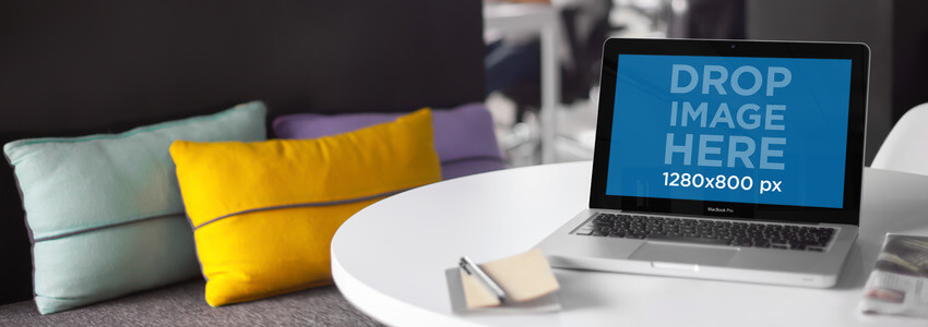 坐在沙發旁邊的桌子上的 Macbook 的筆記本電腦模型