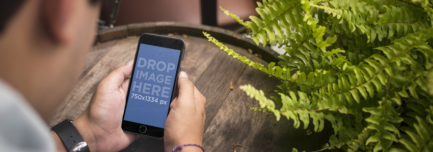 バーの Placeit ステージ イメージで若い男をフィーチャーした黒の iPhone 6 モックアップ