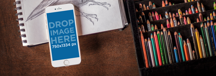 スケッチブック Placeit Stage Image の上に置かれた白い iPhone 6 のモックアップ