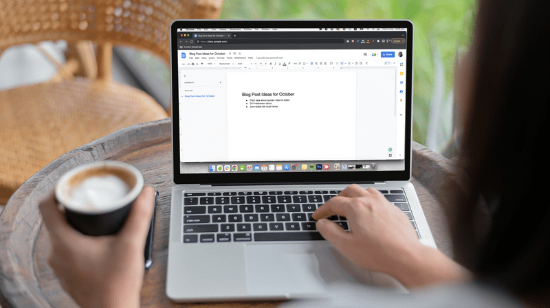 Modell mit einer Frau, die an einem Macbook arbeitet und Kaffee trinkt