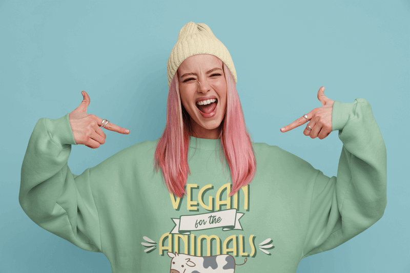 Modell einer Frau mit rosa gefärbtem Haar, die auf ihr Sweatshirt zeigt