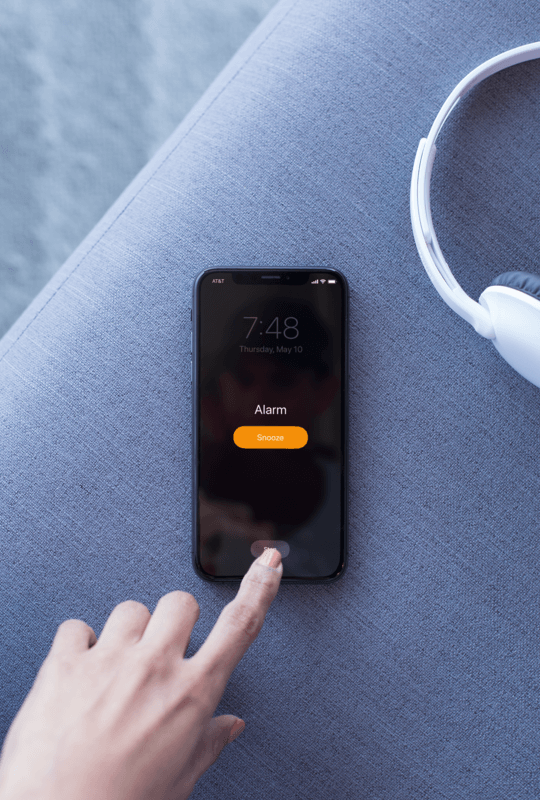 Maquete de um Iphone X descansando em um sofá jogando um podcast
